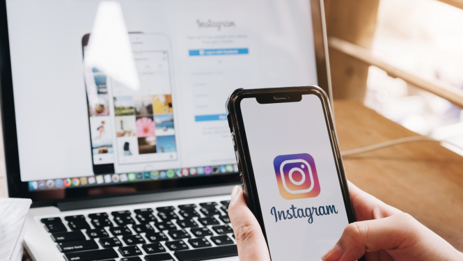 Atvērts portatīvais dators un telefons, kurā redzama Instagram simbolika