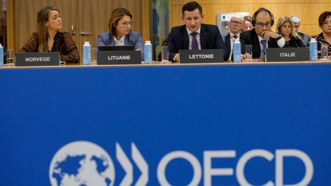 OECD mītiņš - vairāki cilvēki sēž pie galda
