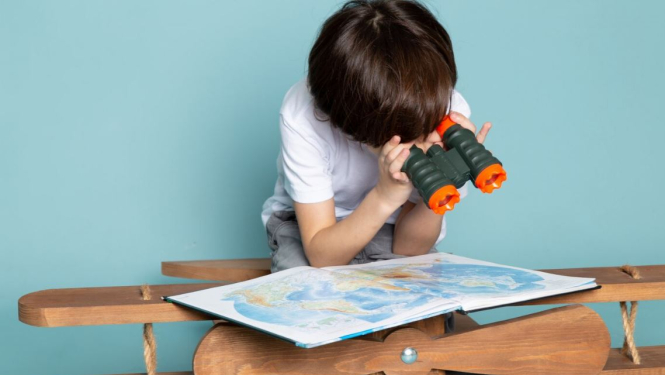 Bērns ar binokli pēta pasaules karti