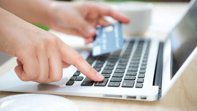 Dators un cilvēka roka ar kredītkarti