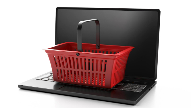 Melns portatīvais dators, uz kura tastatūras uzlikts mazs, sarkans iepirkumu grozs