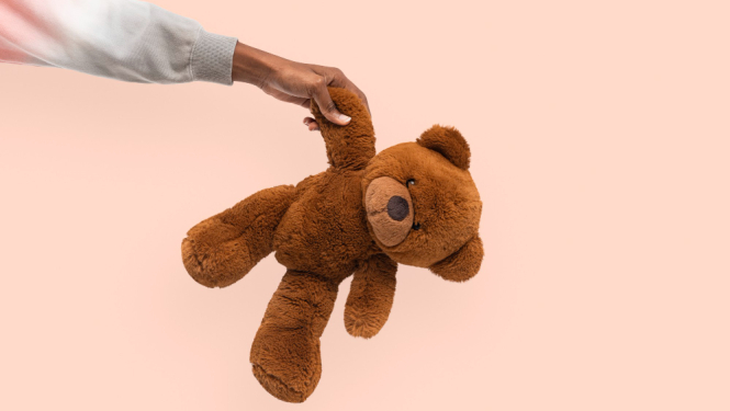 Rotaļu lācis, kuru tur bērna roka