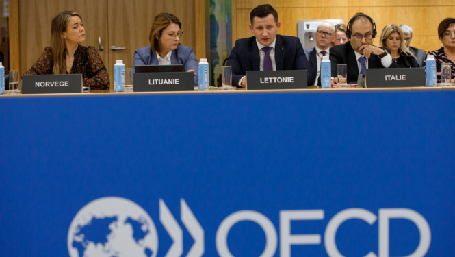 OECD mītiņš - vairāki cilvēki sēž pie galda