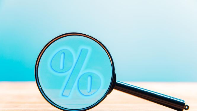 Uz zila fona lupa, aiz kuras redzama procentu zīme