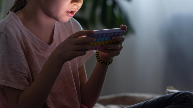 Bērns, kurš spēlē video spēles telefonā