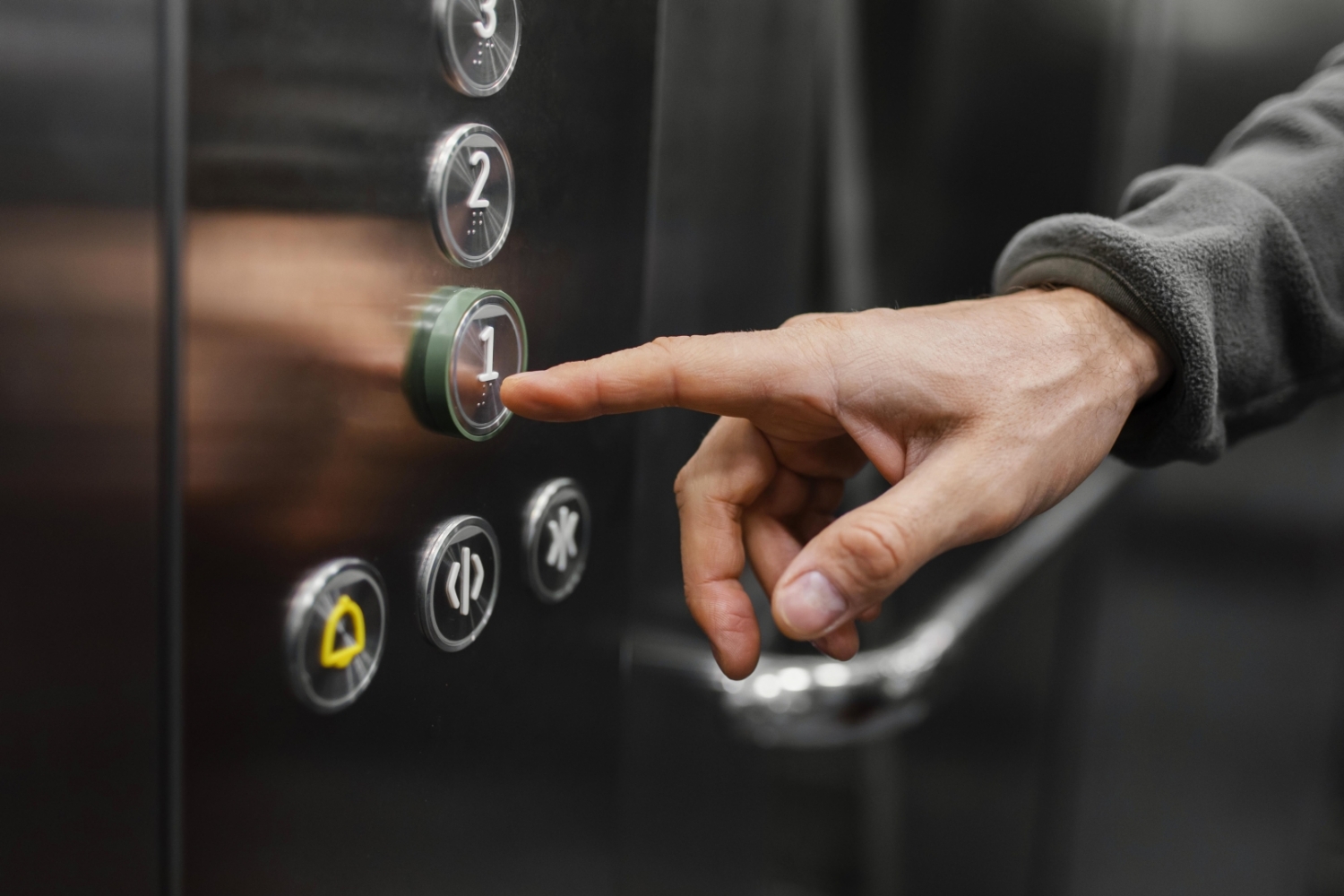 Cilvēka roka nospiež lifta pogu