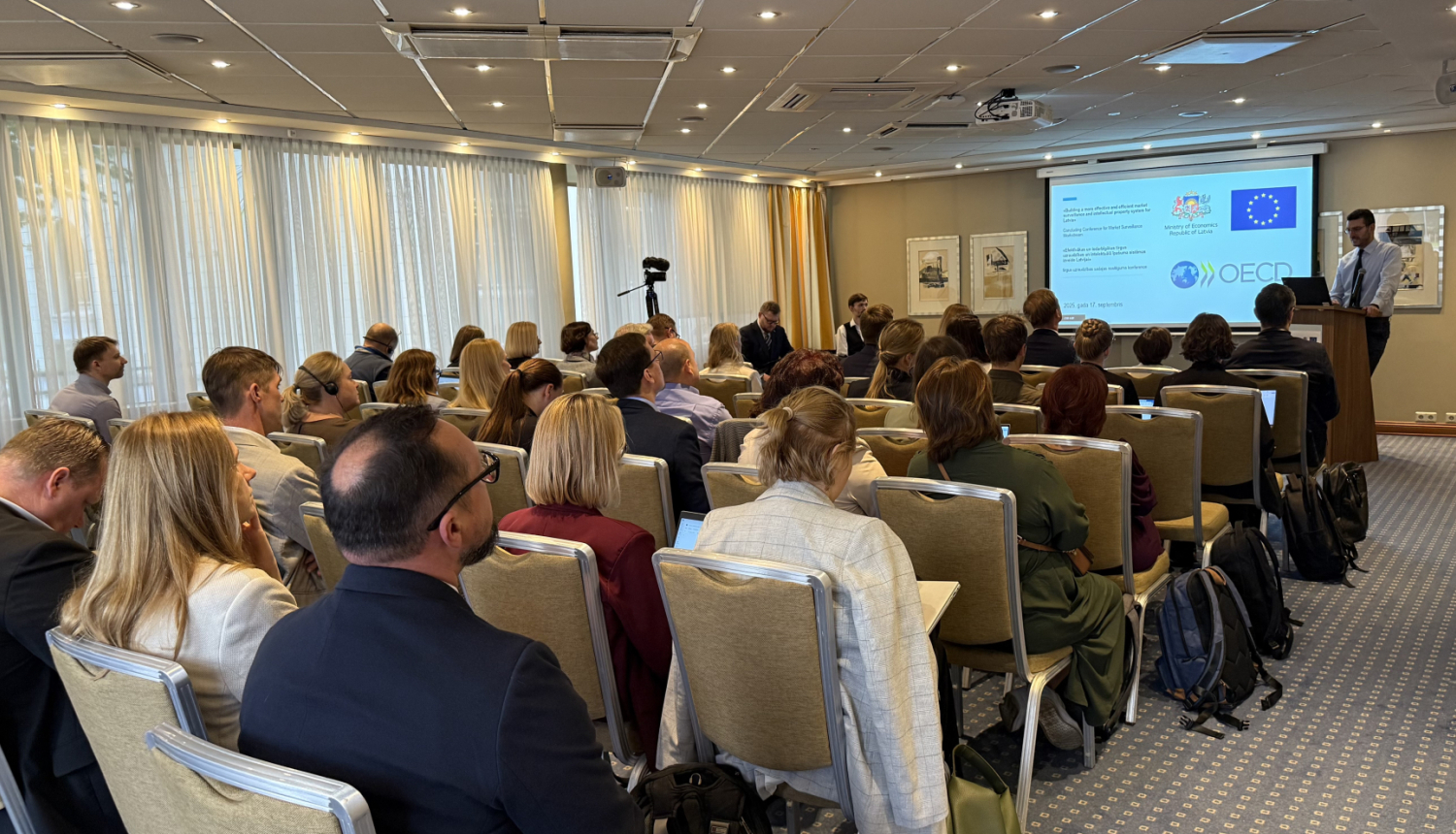 OECD sanāksme, konferenču zāle ar cilvēkiem, priekšā ekrāns